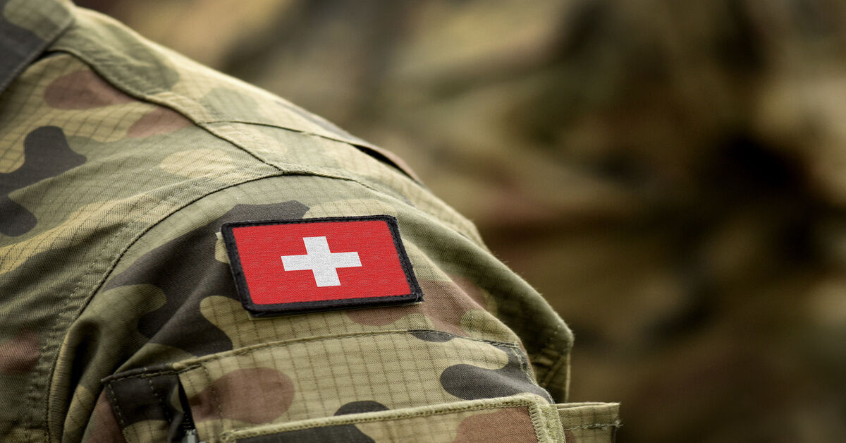 A close-up of the shoulder of a military uniform in green camouflage with a patch of the Swiss flag. A close-up of the shoulder of a military uniform in green camouflage with a patch of the Swiss flag.